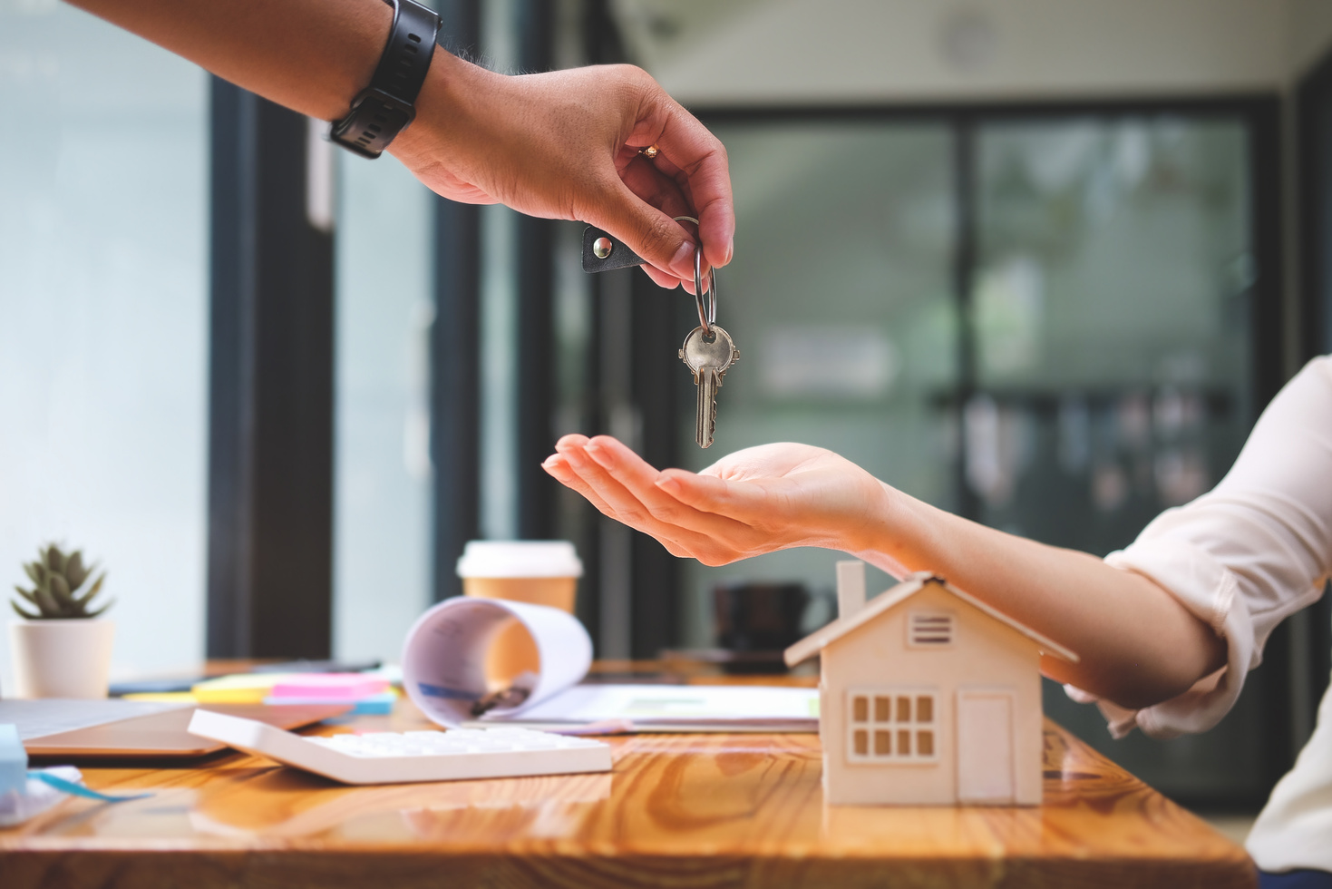 Estate Agent Giving House Keys to New Property Owners after Sign